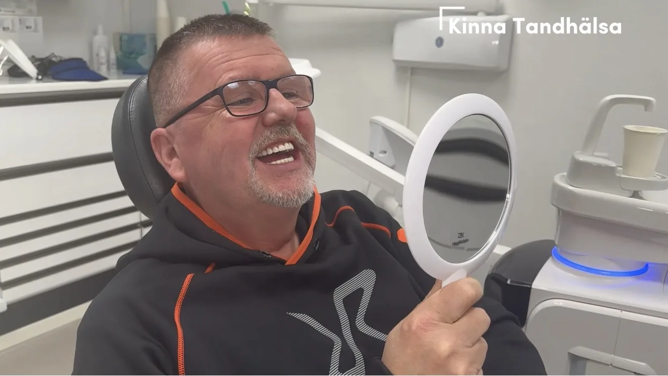 Patient ser sitt nya leende i spegeln i behandlingsrummet på Kinna Tandhälsa